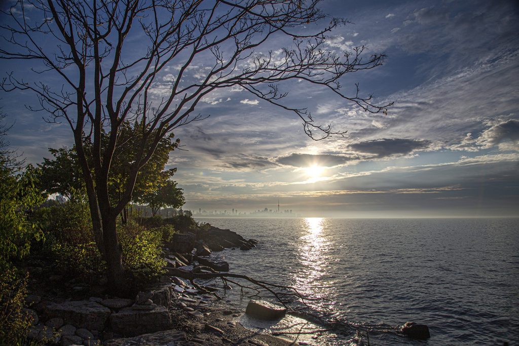 A wide daylight photograph of Lake Ontario’s shoreline with open water, a distant horizon, and a visible coastal landscape