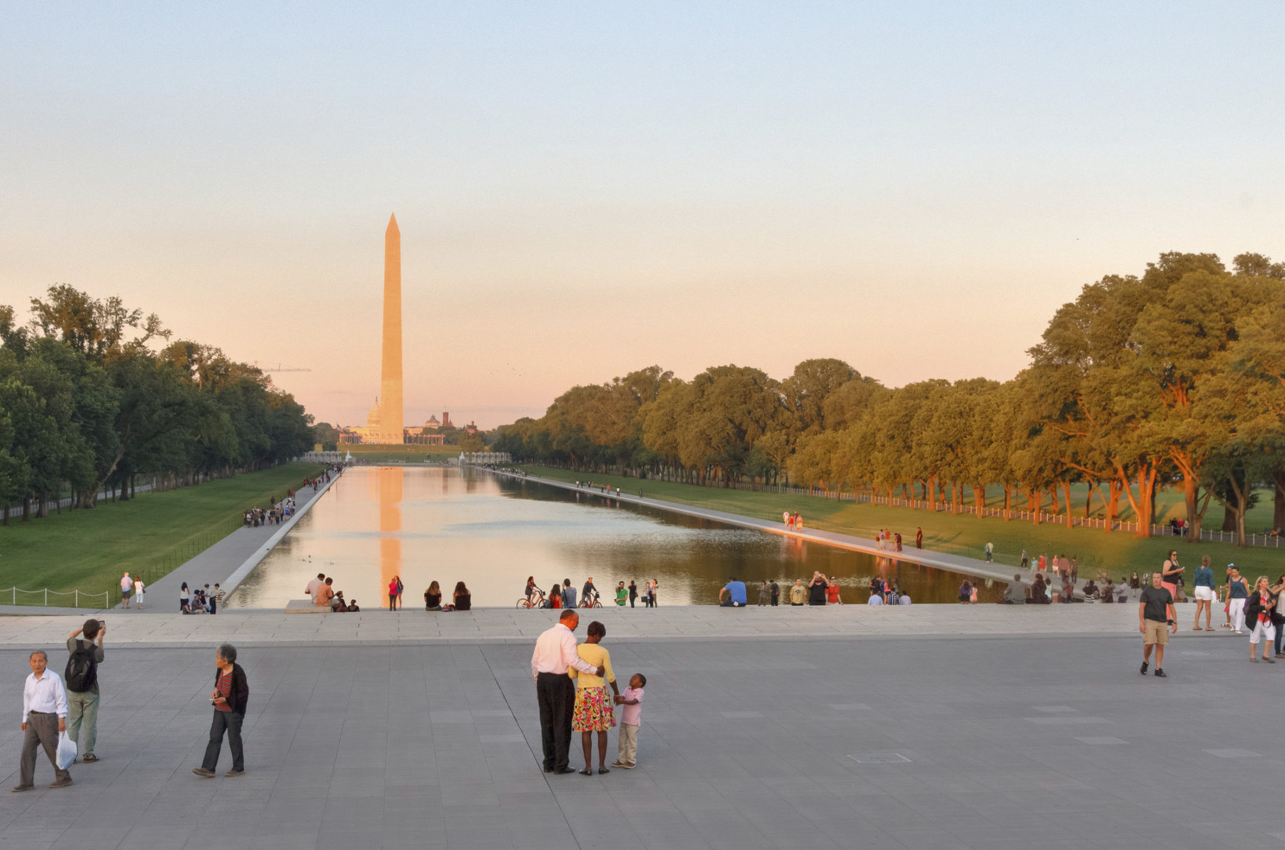 A wide daylight photograph of the Lincoln Memorial Reflecting Pool on the National Mall in Washington, DC, with the water and surrounding walkways visible
