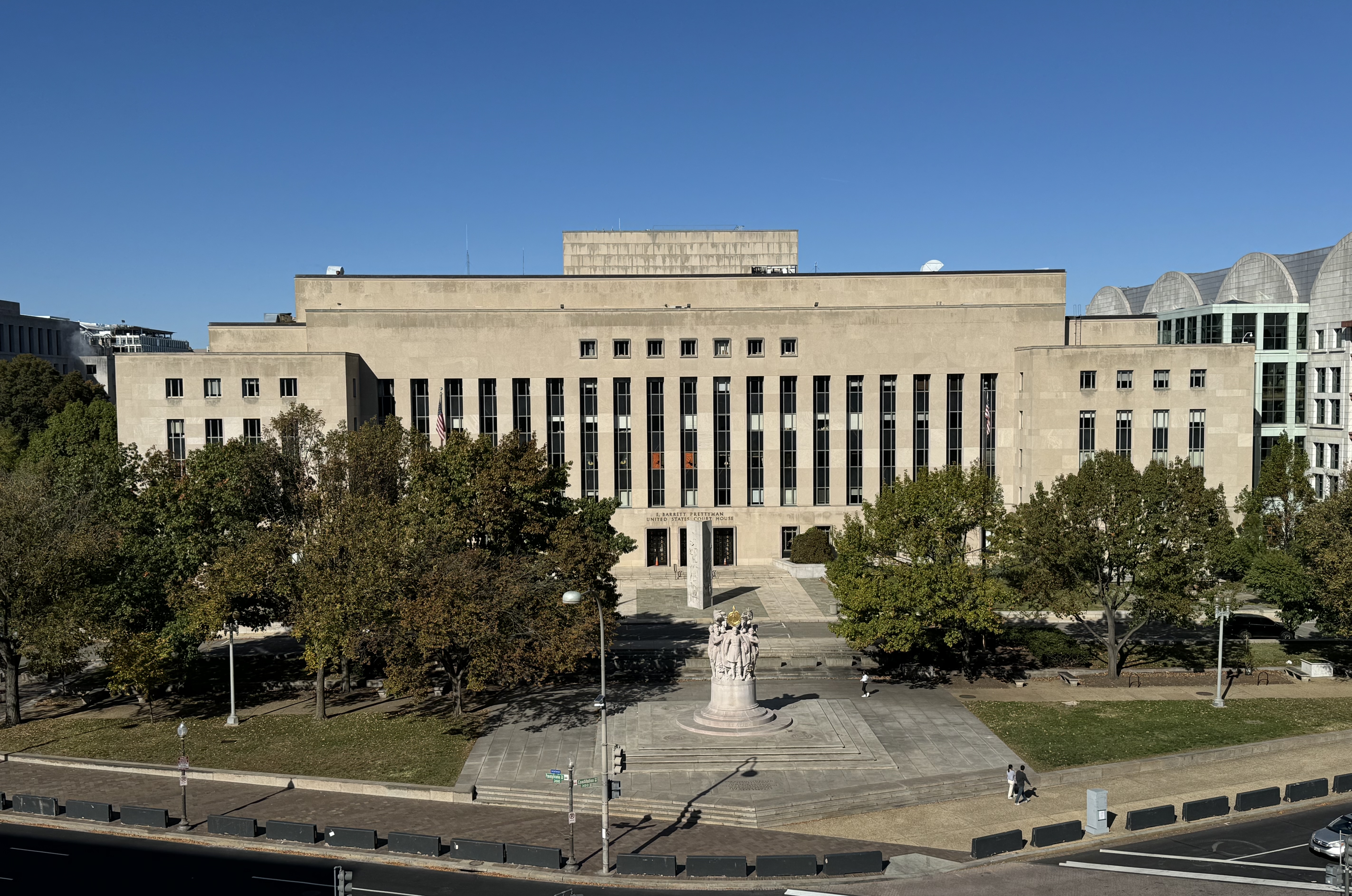 A wide shot of a federal courthouse in Washington, D.C., with the building facade and steps visible on an overcast day, news photography style