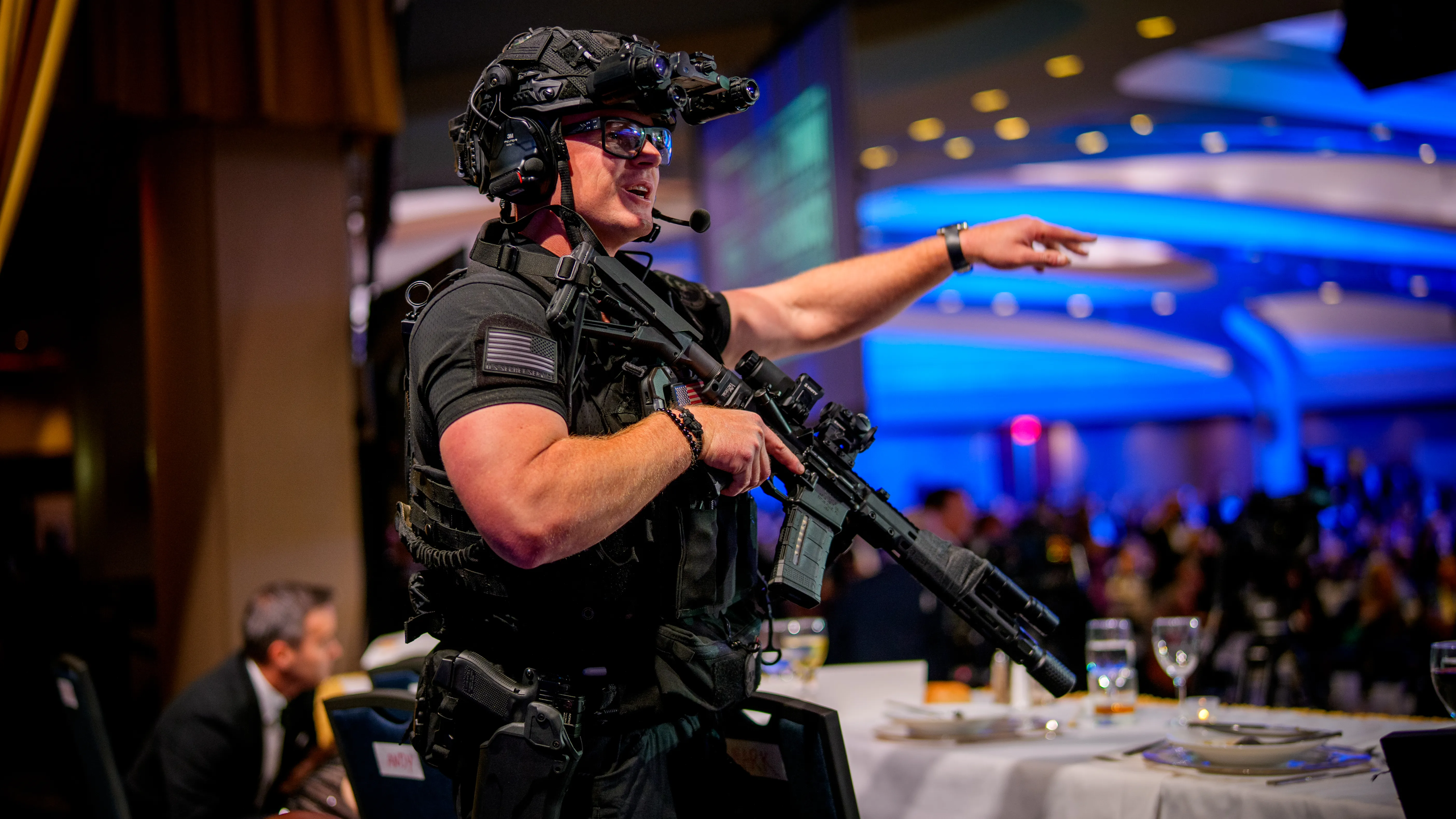 Aishah Hasnie speaking on a phone near a crowded event space, appearing to report live under hectic conditions, news photography style