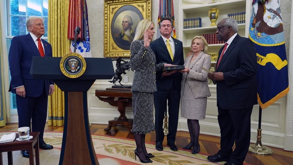 An Attorney General swearing-in ceremony in a formal government setting, with U.S. flags visible behind the speaker