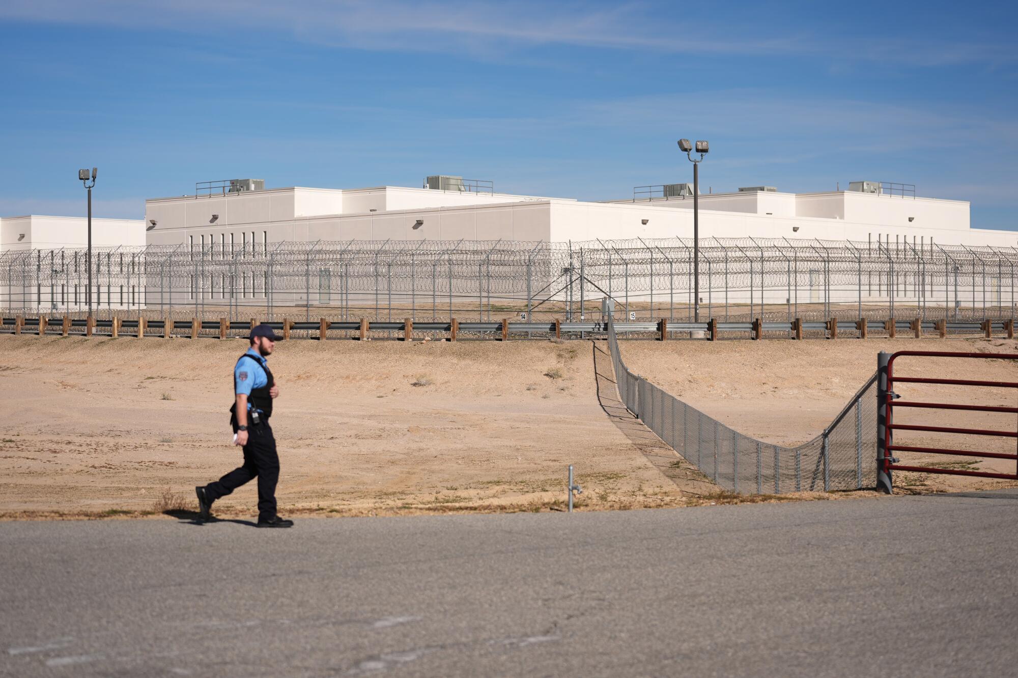 An exterior view of an ICE detention facility, showing perimeter fencing and posted signage in daylight