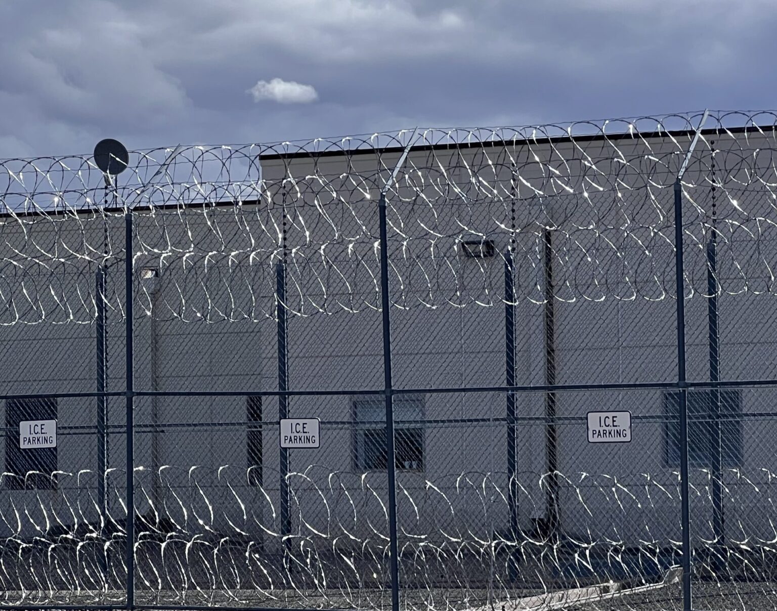 An exterior view of an ICE immigration detention facility with visible perimeter fencing