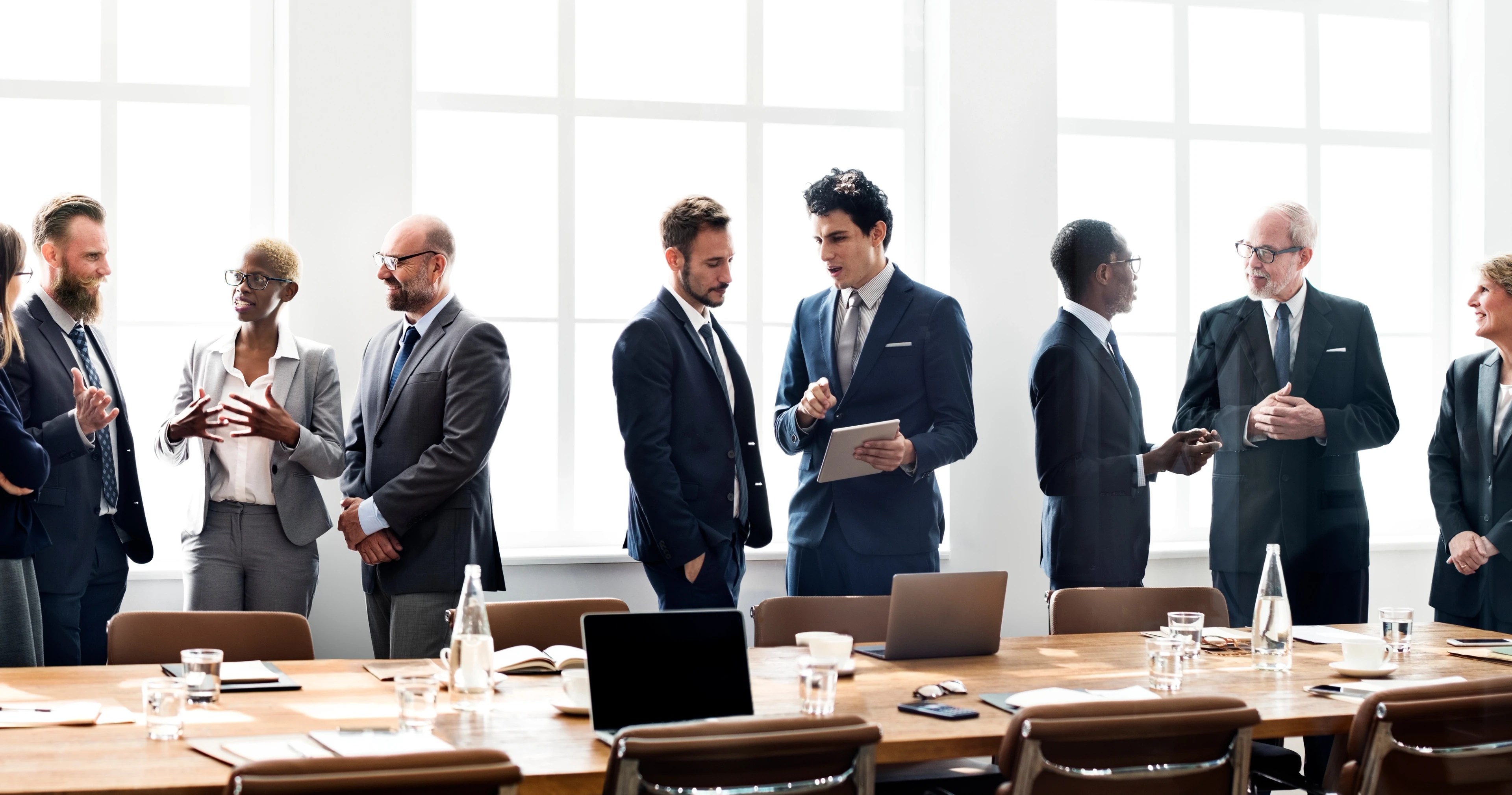 An in-house attorney speaking with executives around a conference table in a corporate boardroom during a private meeting, candid photography