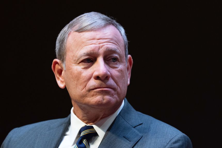 Chief Justice John Roberts speaking at a legal conference podium in Hershey, Pennsylvania in 2026, candid event photography style