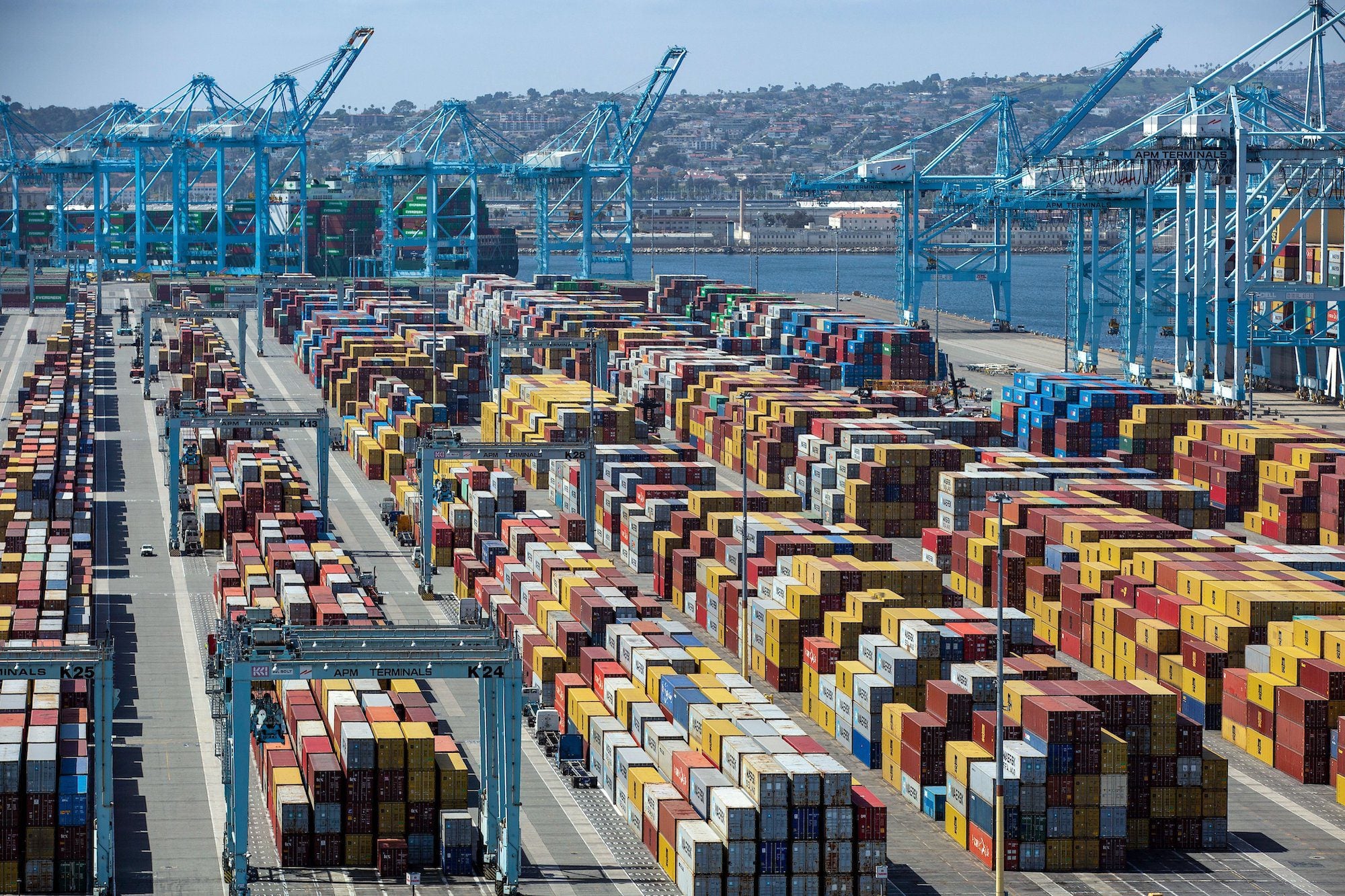 Container ships and stacked cargo containers at the Port of Los Angeles with cranes in the background