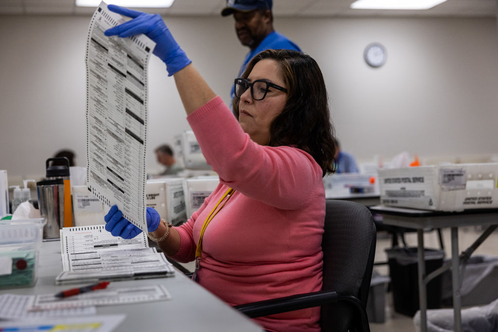 Election workers sorting and scanning paper ballots at a county election office on election night in the United States, news photography style