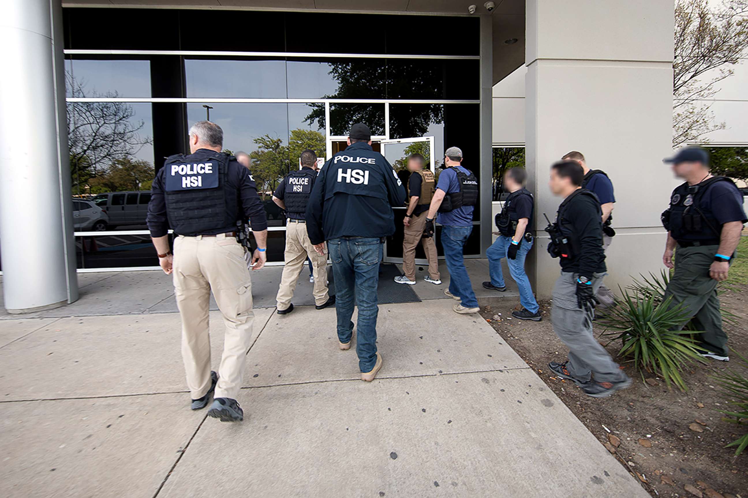 Federal immigration agents associated with ICE Enforcement and Removal Operations standing outside a commercial building entrance during an enforcement action