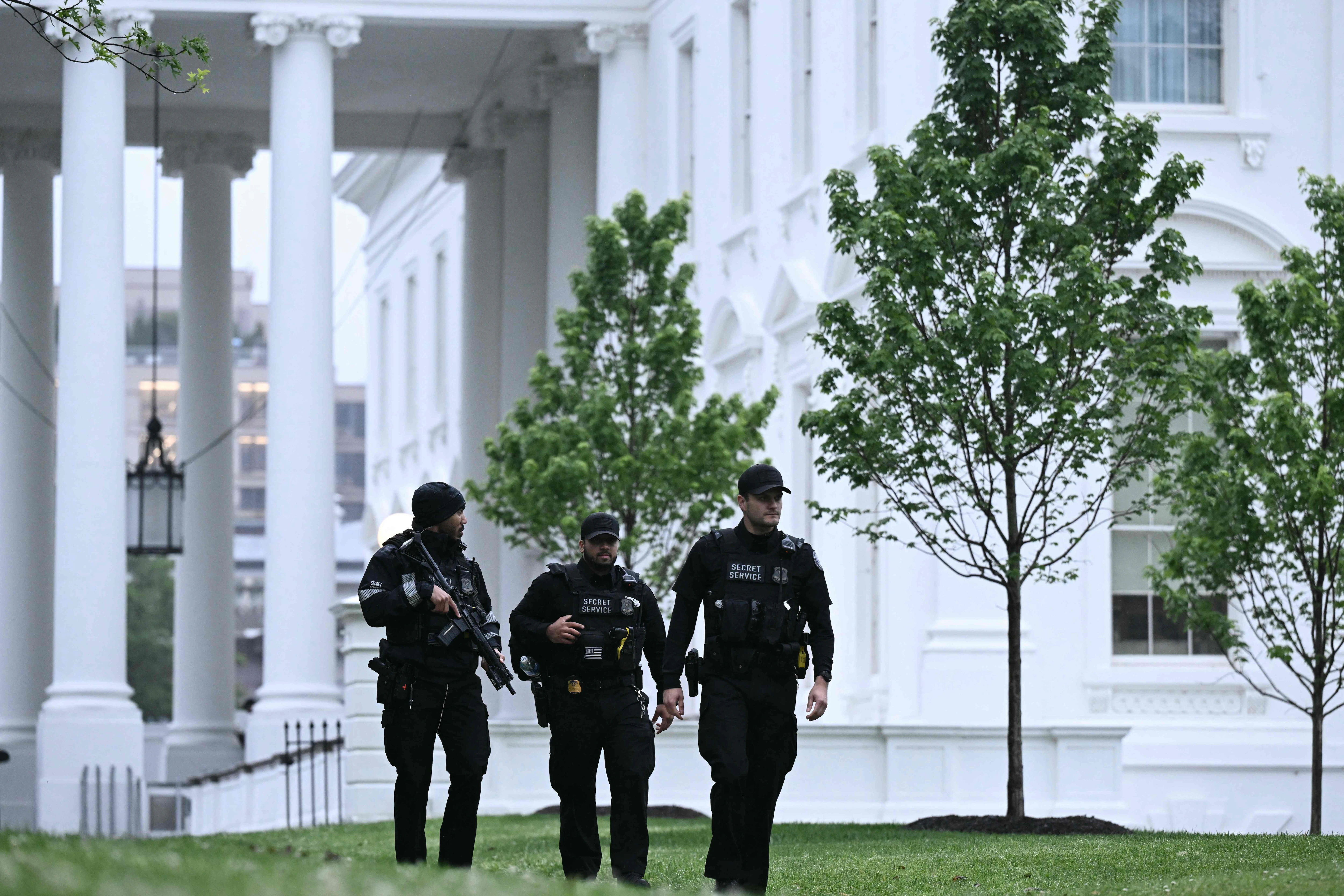 Federal law enforcement officers responding outside the White House grounds at dusk in Washington, D.C., with a visible security perimeter and agents moving quickly