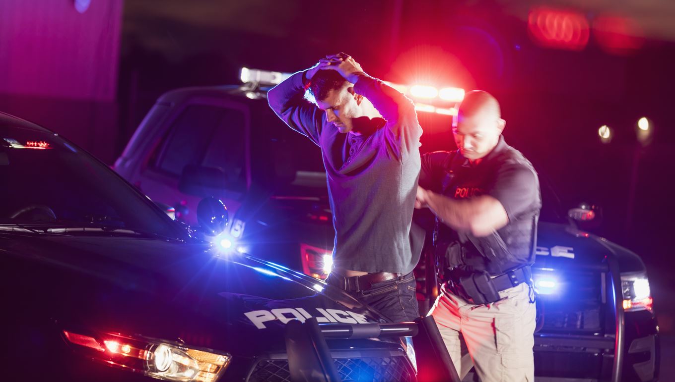 ICE Enforcement and Removal Operations officers conducting a public arrest operation near vehicles, with agents wearing identifying vests
