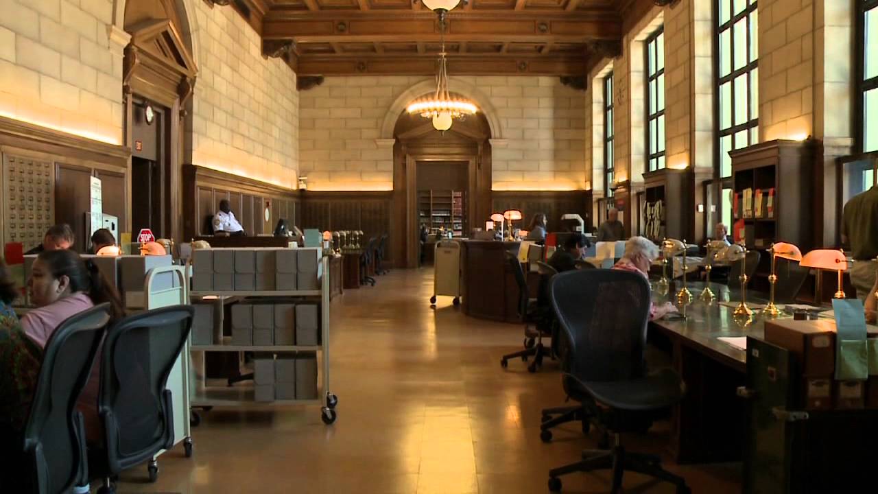 Illustration of a National Archives style reading room with researchers seated at tables and archival storage boxes visible in the background under bright indoor lighting