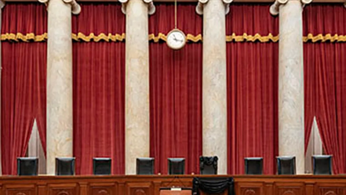Inside the United States Supreme Court courtroom with the justices' bench visible and empty, warm lighting, news photography style
