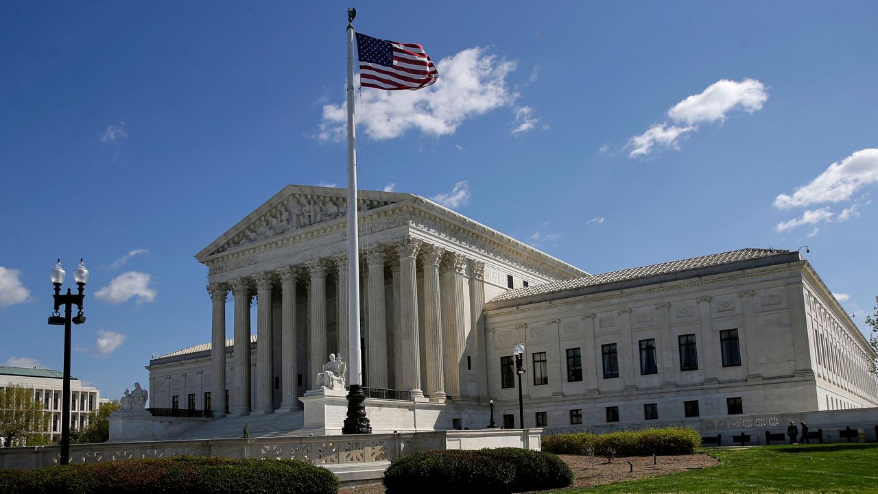 John Durnell, an older man in a suit, standing outside the U.S. Supreme Court building in Washington, DC, with the courthouse steps behind him, news photography style