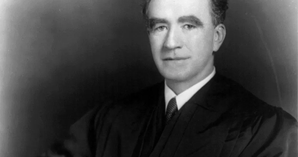 Justice Frank Murphy in a formal seated portrait setting from the 1940s, wearing judicial attire, news photography style