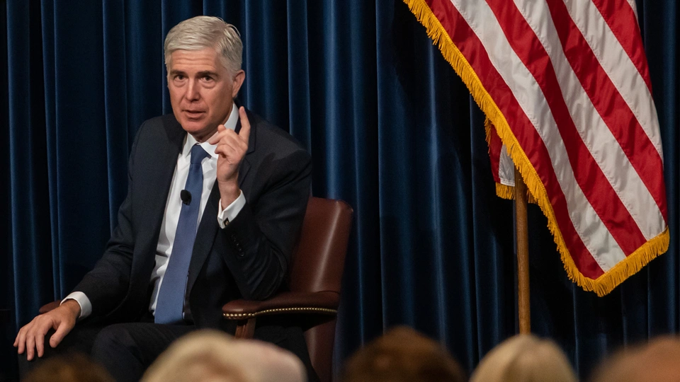 Justice Neil Gorsuch standing inside the Supreme Court building in Washington, formal news photography style
