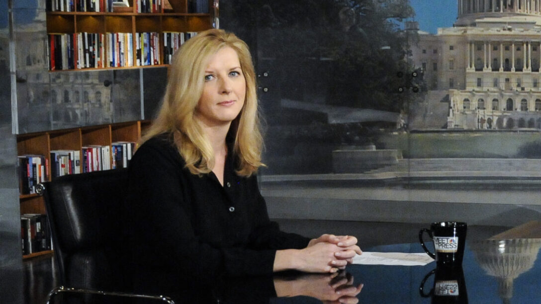 Kathryn Ruemmler walking into a government office building for a congressional interview, carrying a folder and accompanied by an aide, news photography style