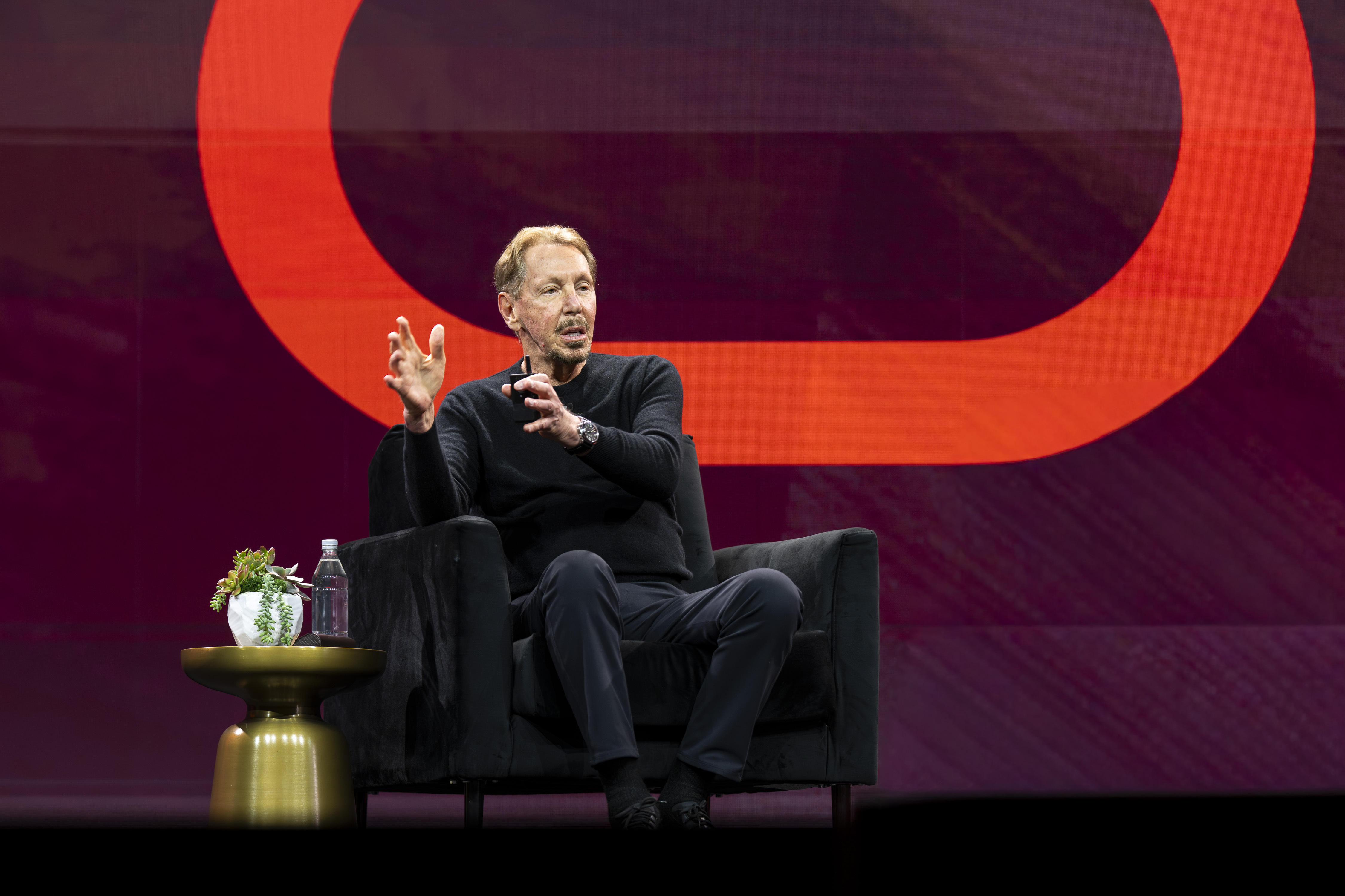 Larry Ellison speaking on stage at an Oracle OpenWorld event with Oracle branding visible