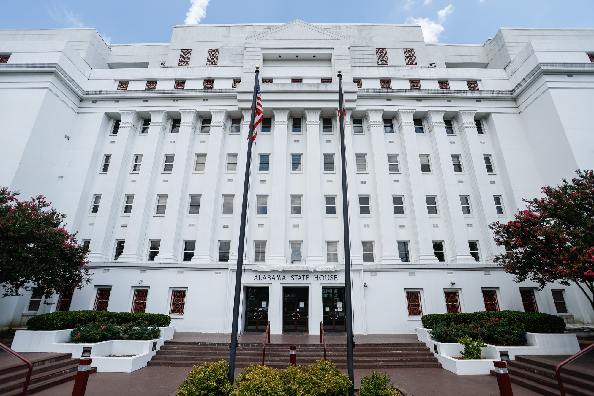 Lawmakers and staff at the Alabama State House during a redistricting discussion, with a congressional district map visible