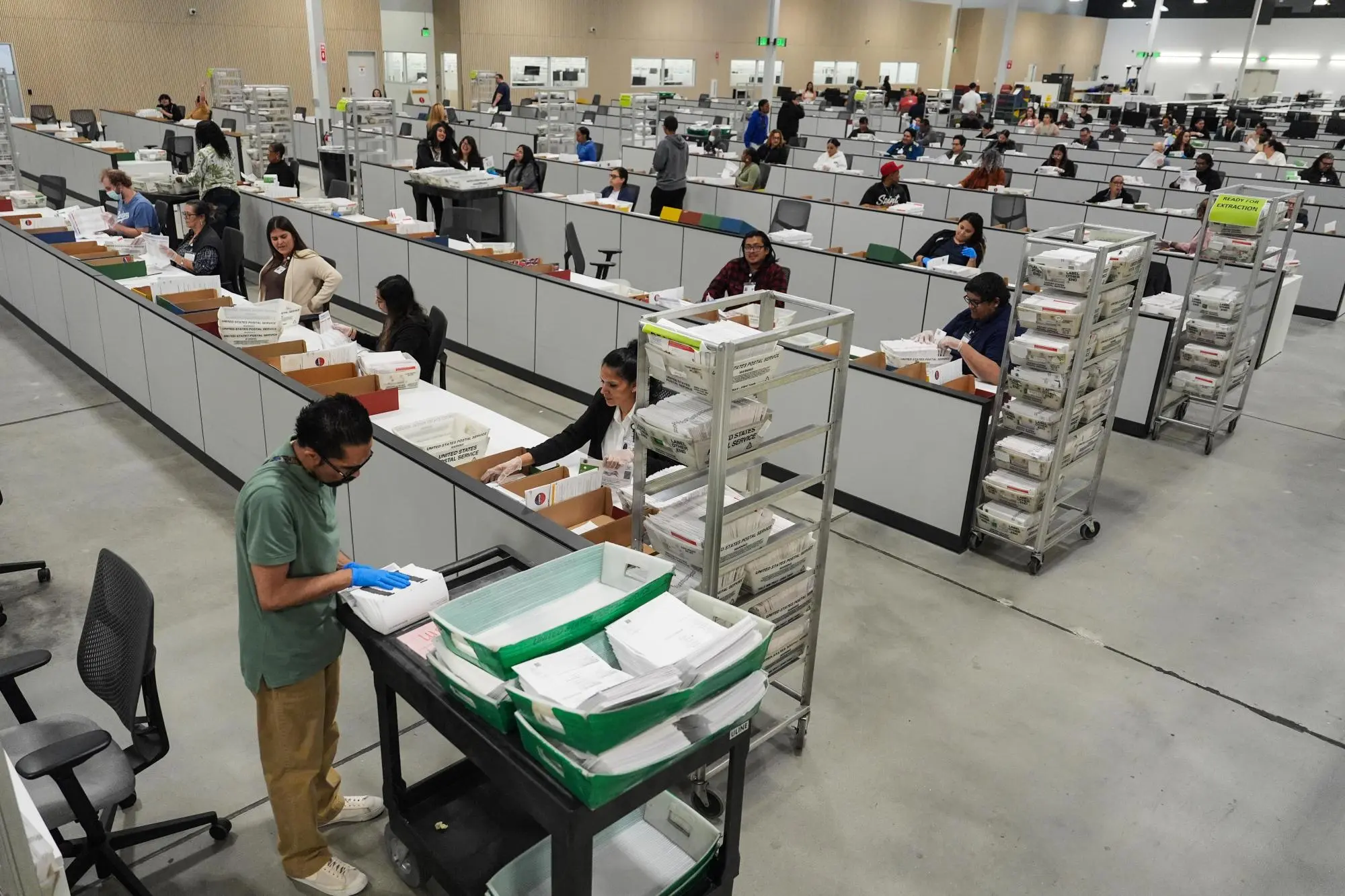Local election workers reviewing and verifying mail ballot envelopes as part of signature verification and processing procedures