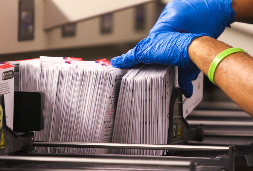 Mail sorting equipment inside a USPS processing facility where Intelligent Mail barcodes are scanned during processing.