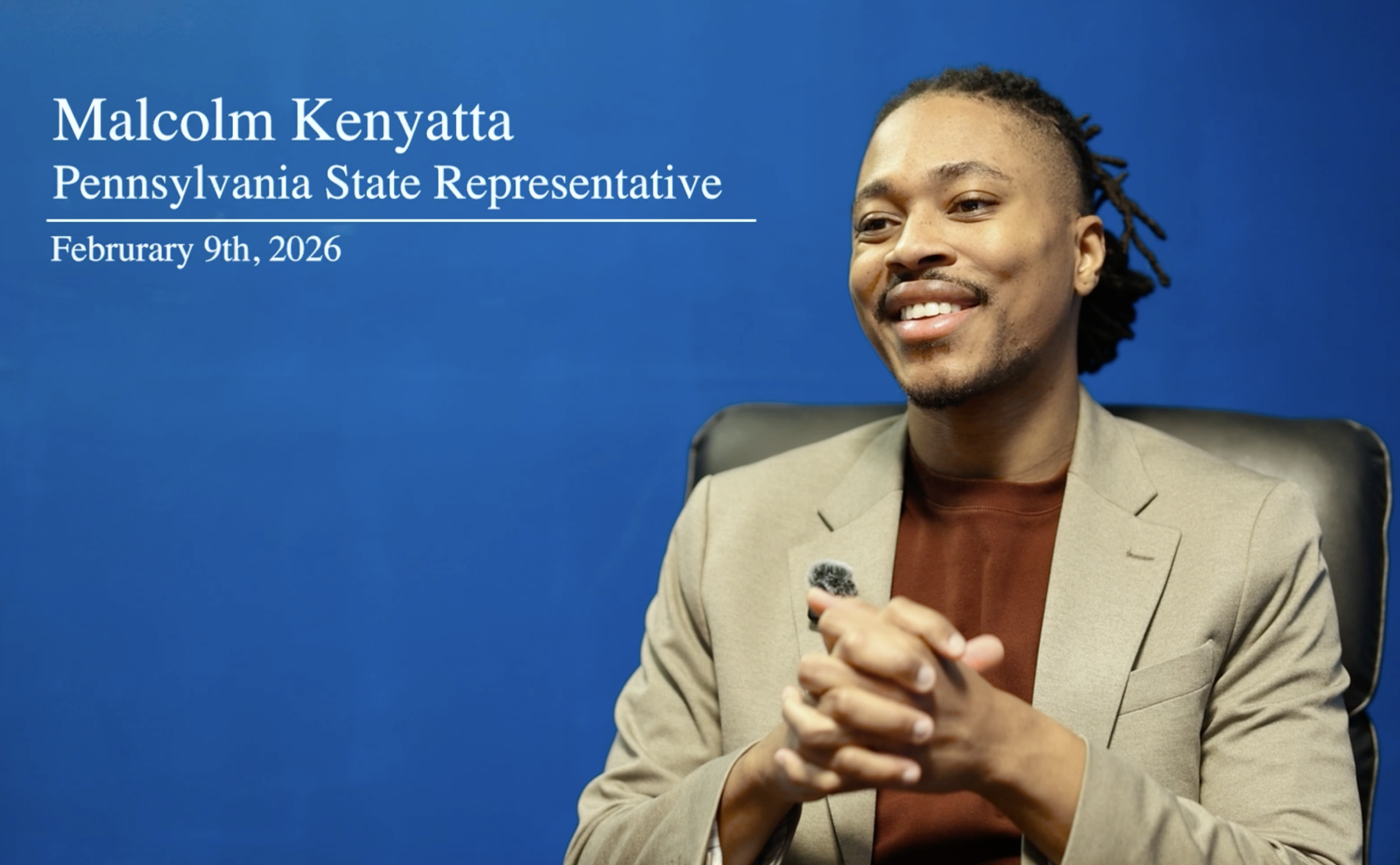 Malcolm Kenyatta speaking at a public event in Pennsylvania, standing at a microphone in a crowded indoor venue, news photography style