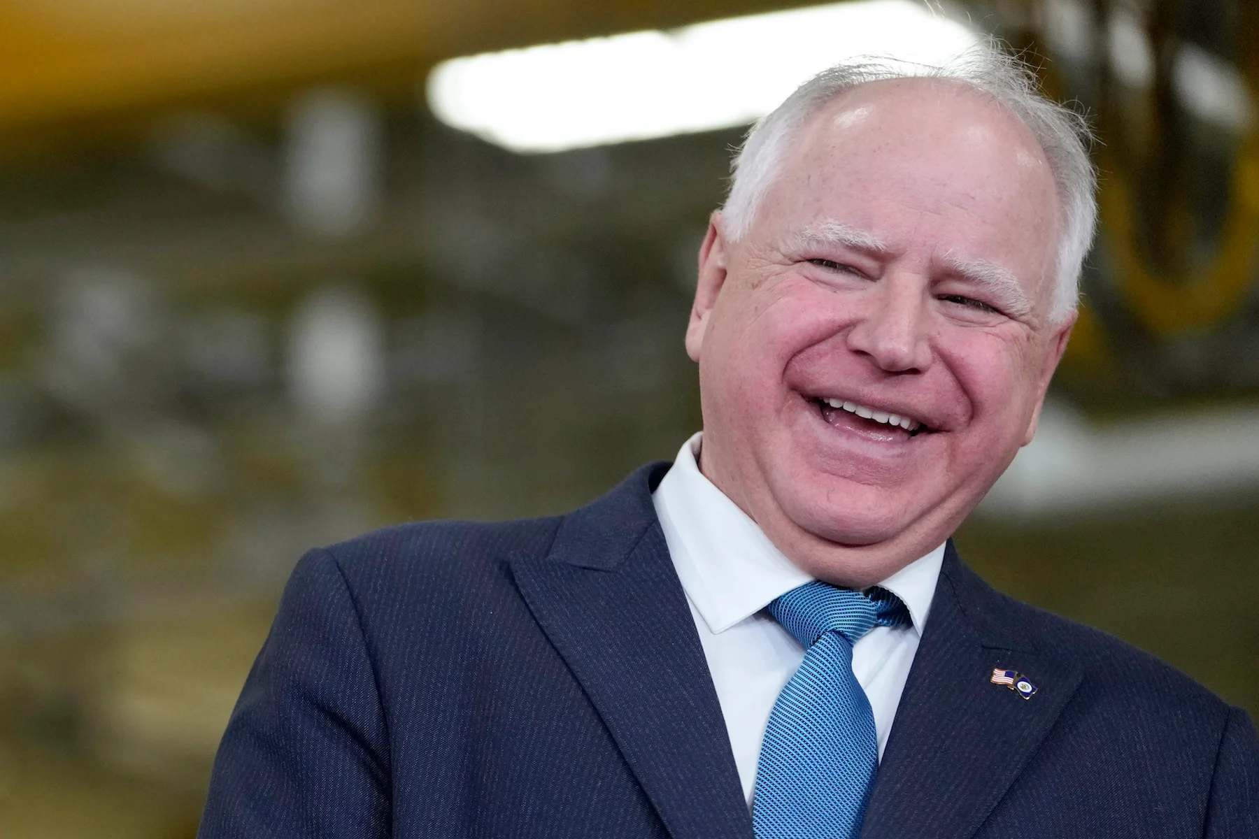 Minnesota Governor Tim Walz speaking at a public event in Minnesota, photographed at a podium with state flags visible