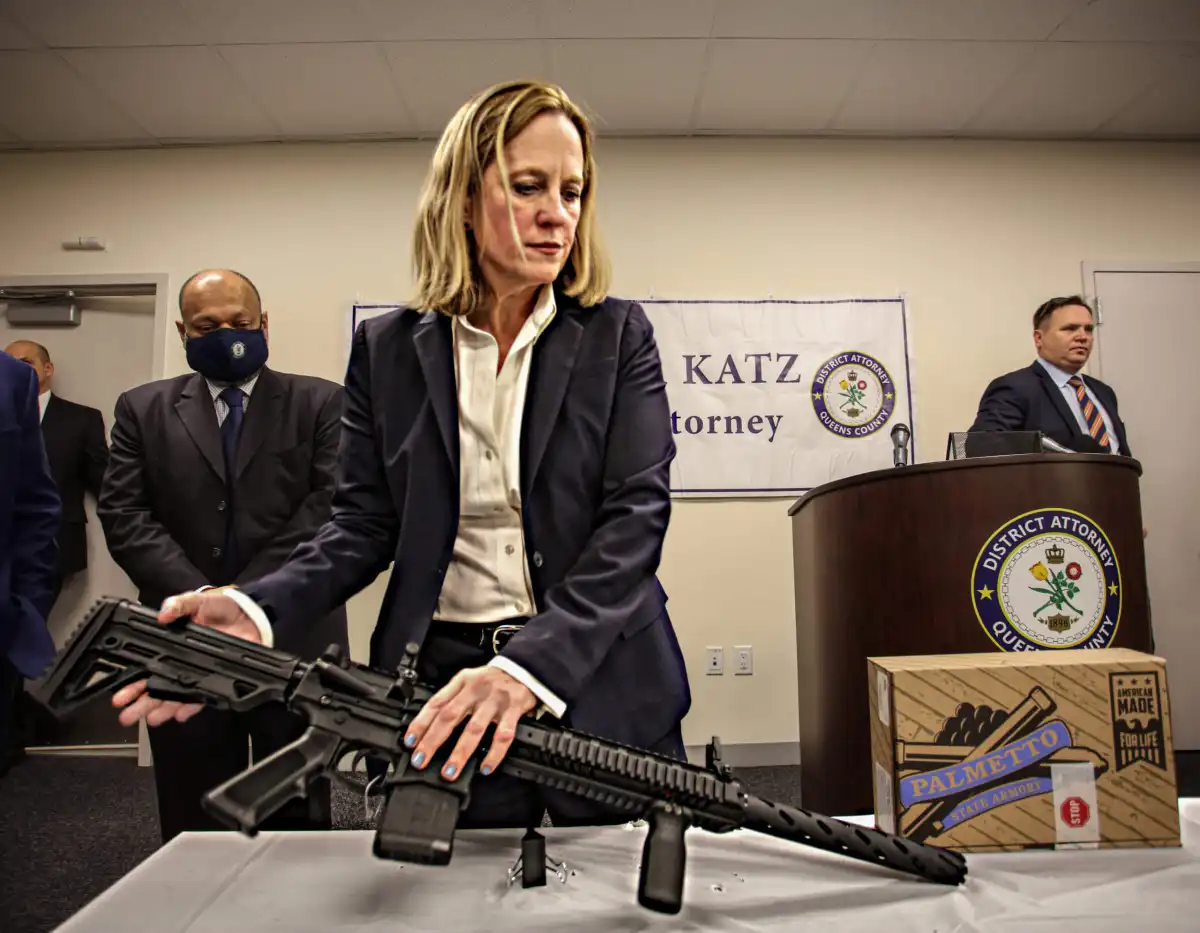 NYPD officers standing behind a table displaying recovered firearms at a public briefing.