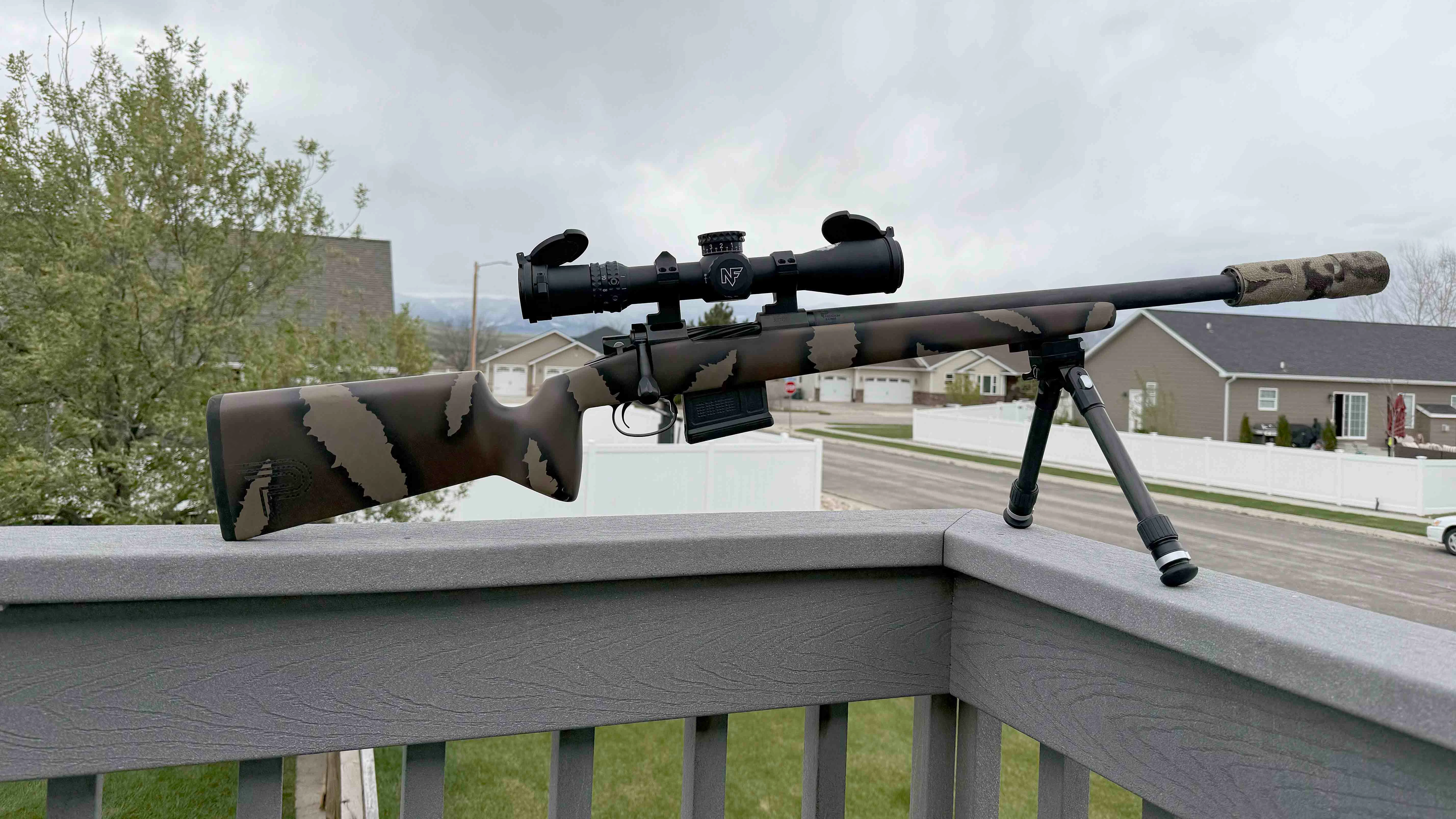 Nic George standing behind a table with firearm parts and tools arranged neatly, in a workshop setting, documentary news photo style