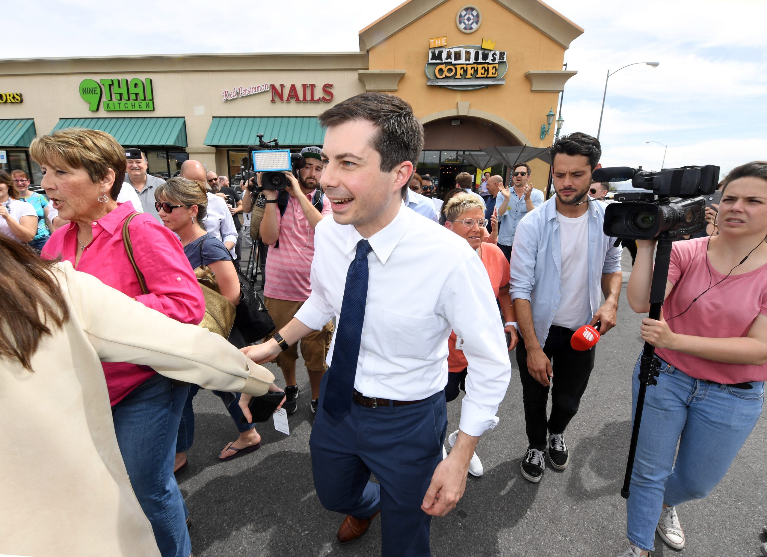 Pete Buttigieg greeting attendees at a campaign-style public event in a crowded room