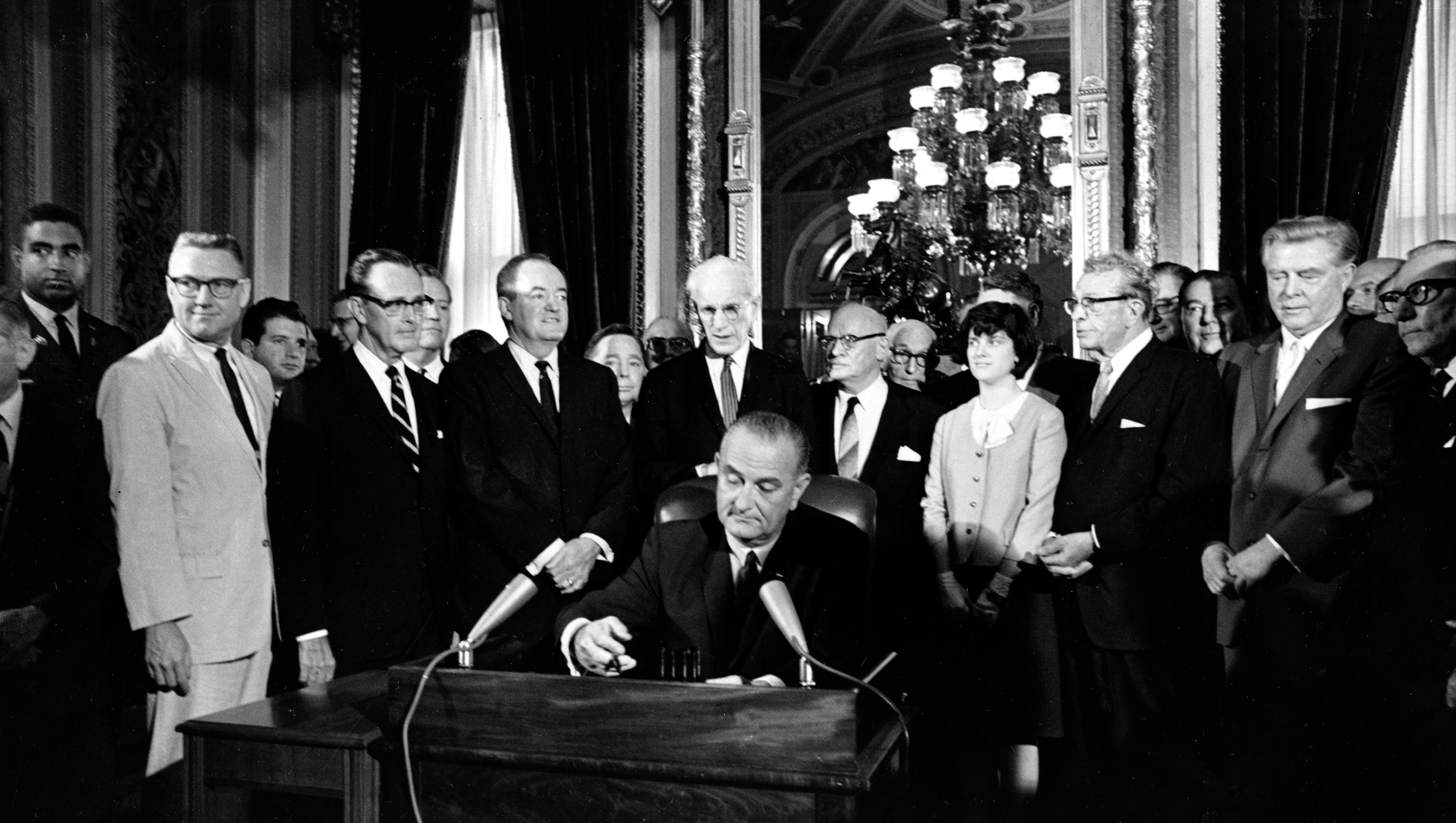 President Donald Trump seated at a desk signing an executive order