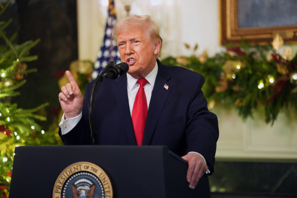 President Donald Trump speaking at a lectern at the White House, with flags behind him, in a straightforward photograph