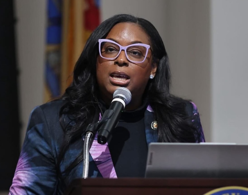 Rep. LaMonica McIver speaking at a podium during a press availability, answering questions from reporters