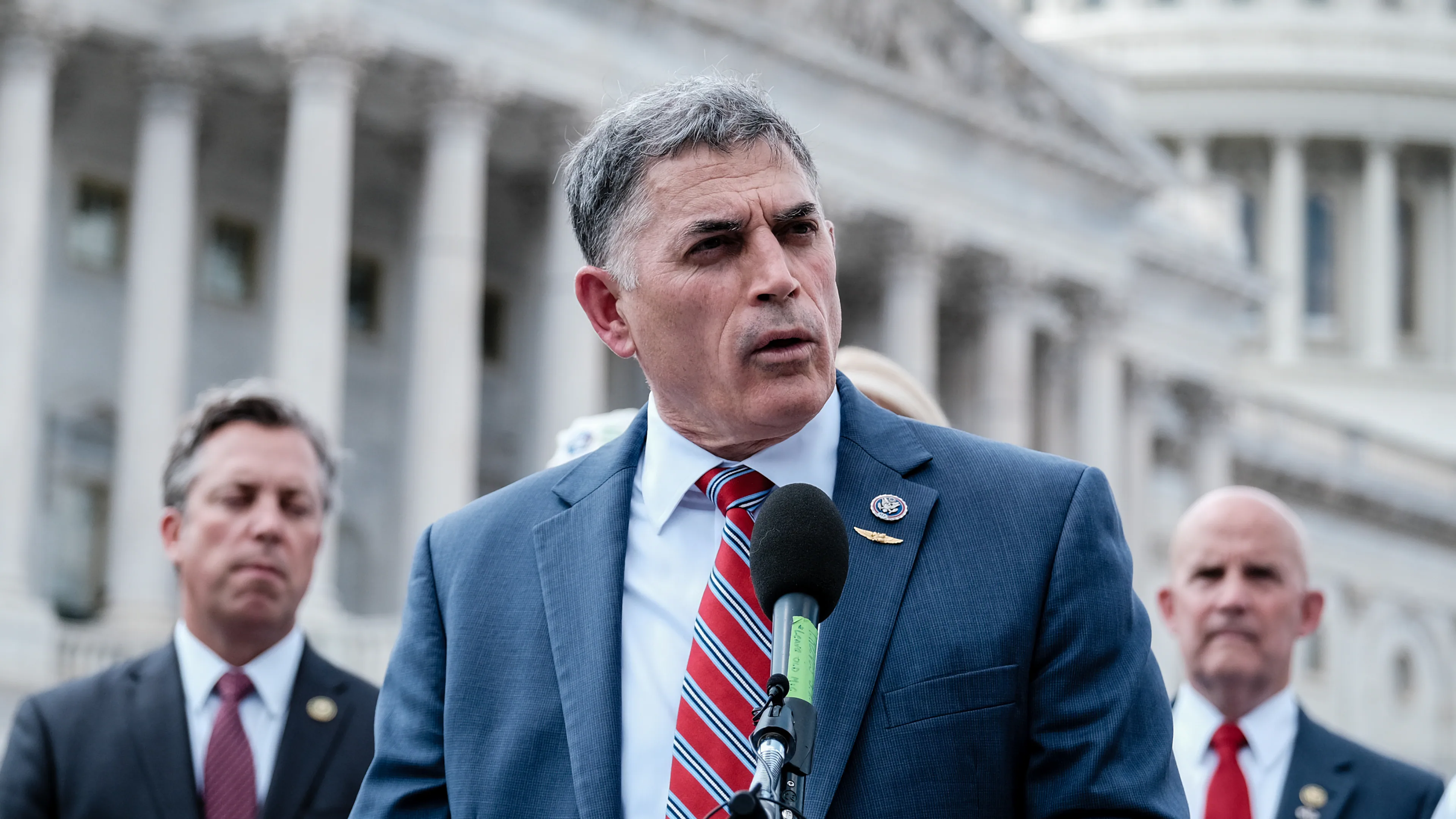 Representative Andrew Clyde speaking to reporters in a hallway on Capitol Hill, news photography style
