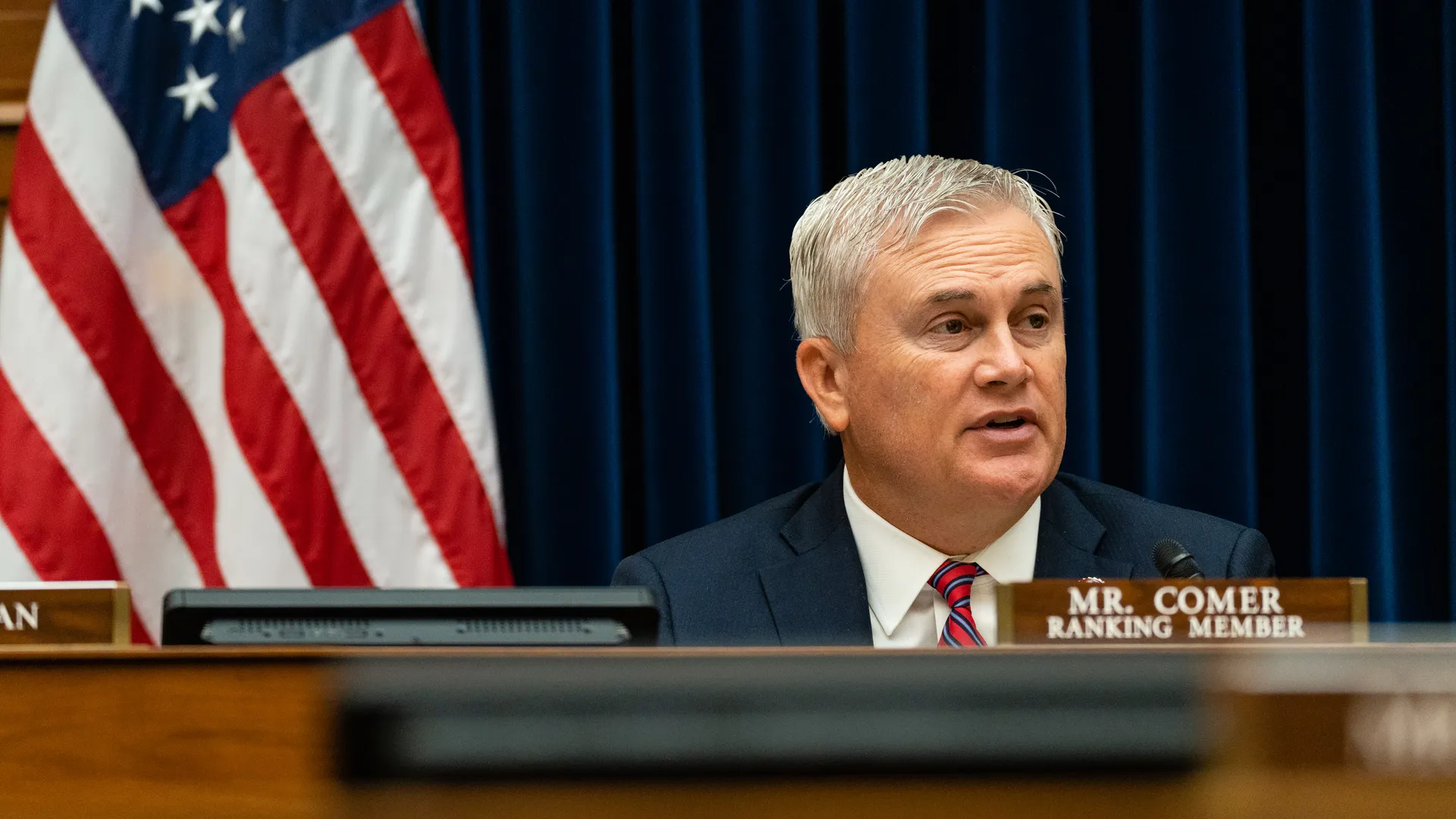 Representative James Comer seated at the dais during a House Oversight Committee hearing, gavel and microphones visible, news photography style
