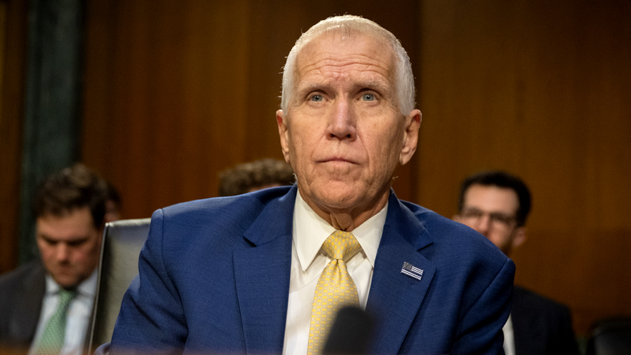 Sen. Thom Tillis speaking into a microphone at a Senate committee dais during a formal hearing, news photography style