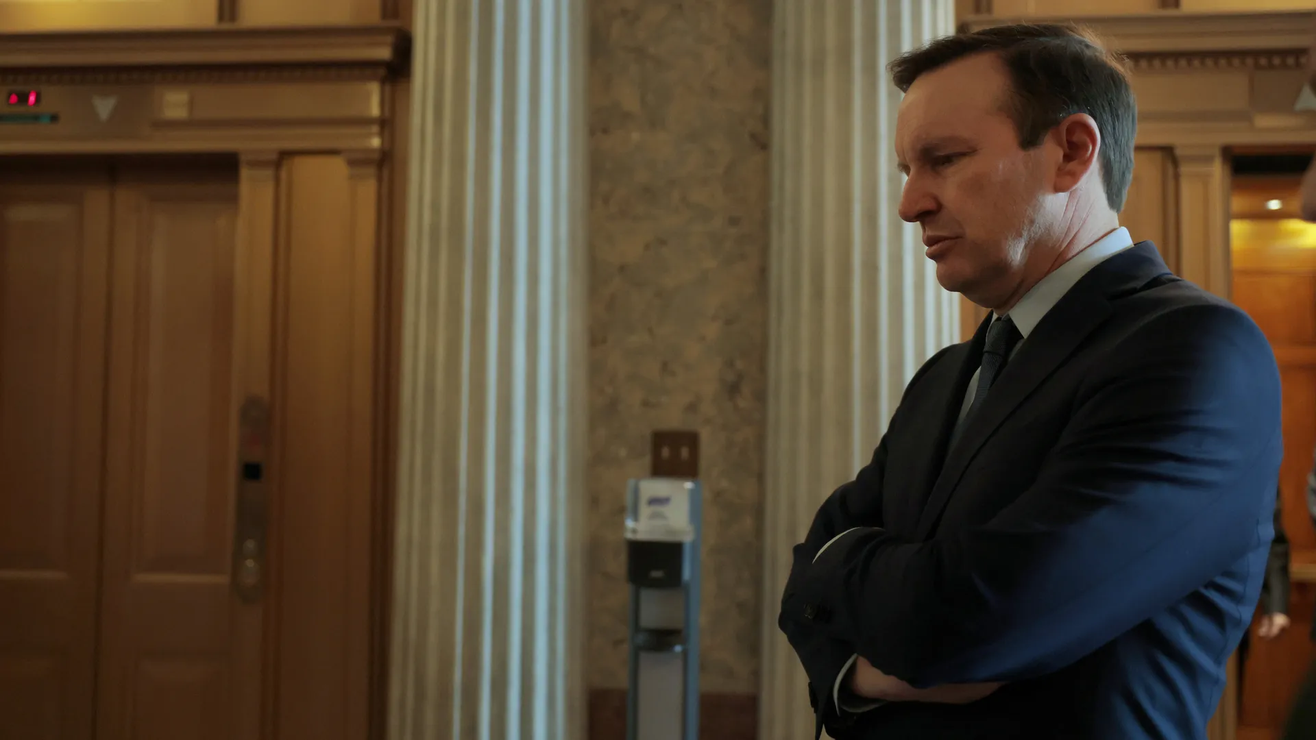 Senator Chris Murphy speaking to reporters in a U.S. Capitol hallway, microphones held toward him, news photography style