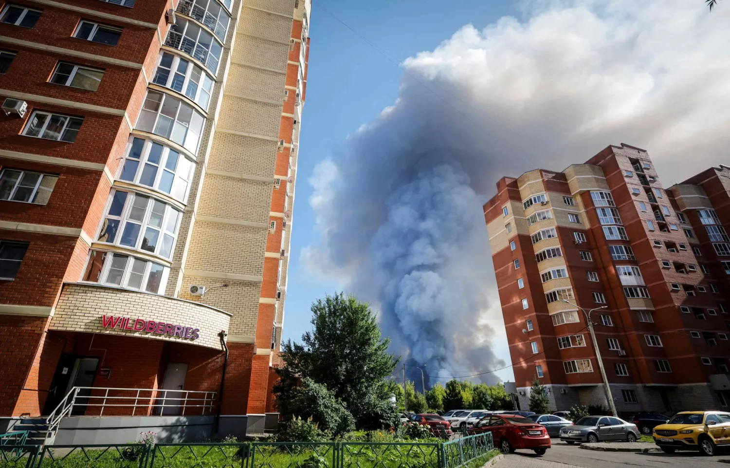 Smoke rising from an industrial warehouse complex in Elektrostal in the Moscow region after a reported drone strike, with emergency vehicles visible near the perimeter