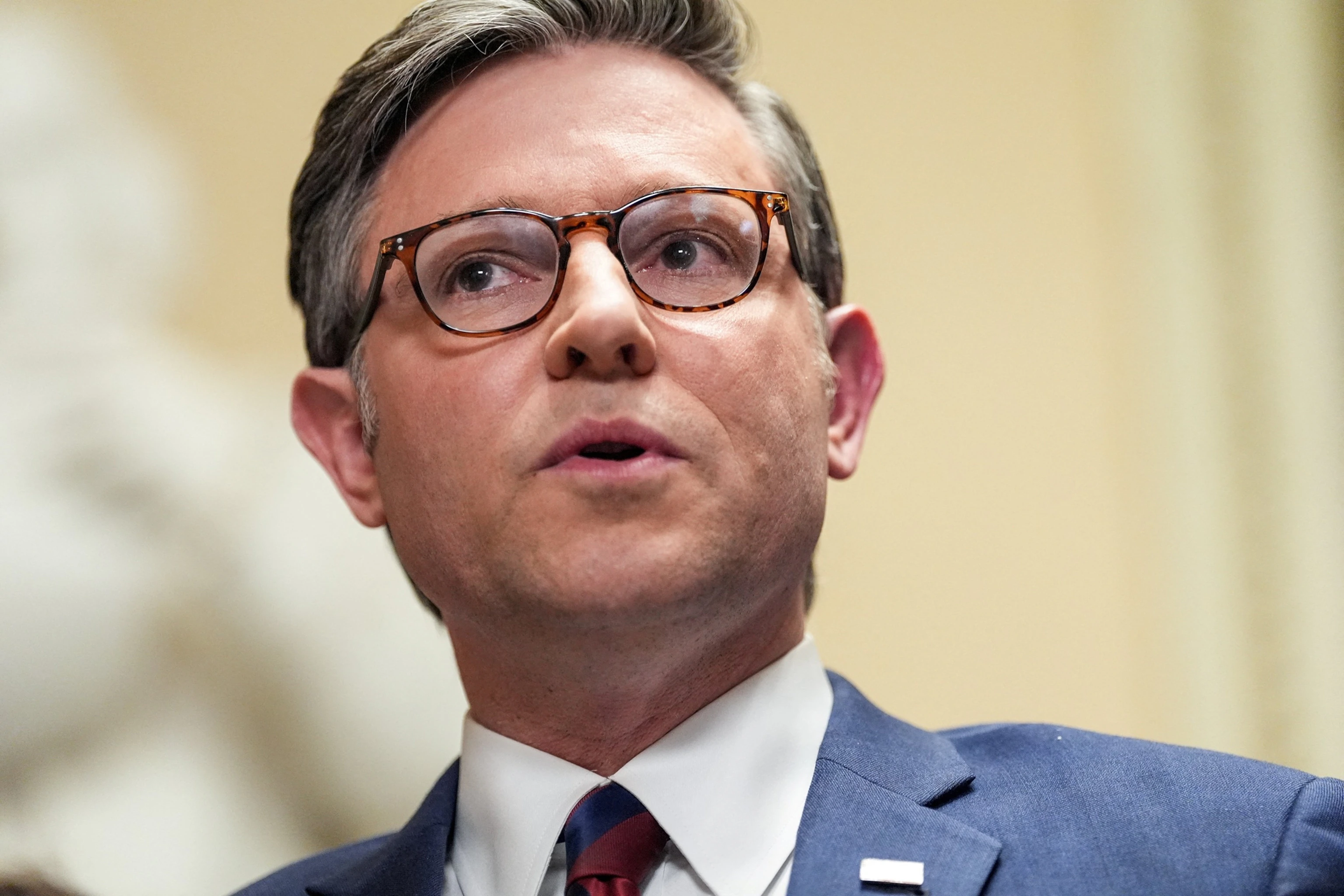 Speaker Mike Johnson walking through the U.S. Capitol with reporters nearby, news photography style