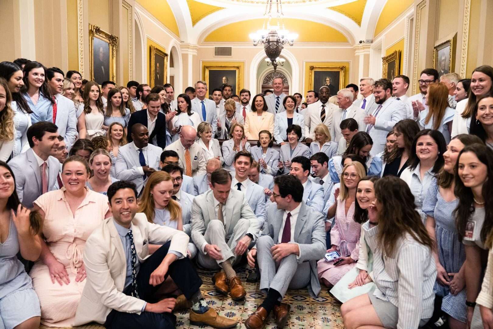 Staffers walking through a corridor near the United States Senate side of the Capitol, carrying folders and talking quietly, news photography style