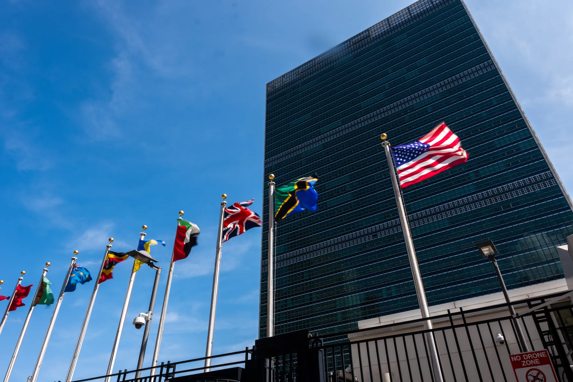 The American flag flying outside the United Nations headquarters in New York City on a clear day, news photography style