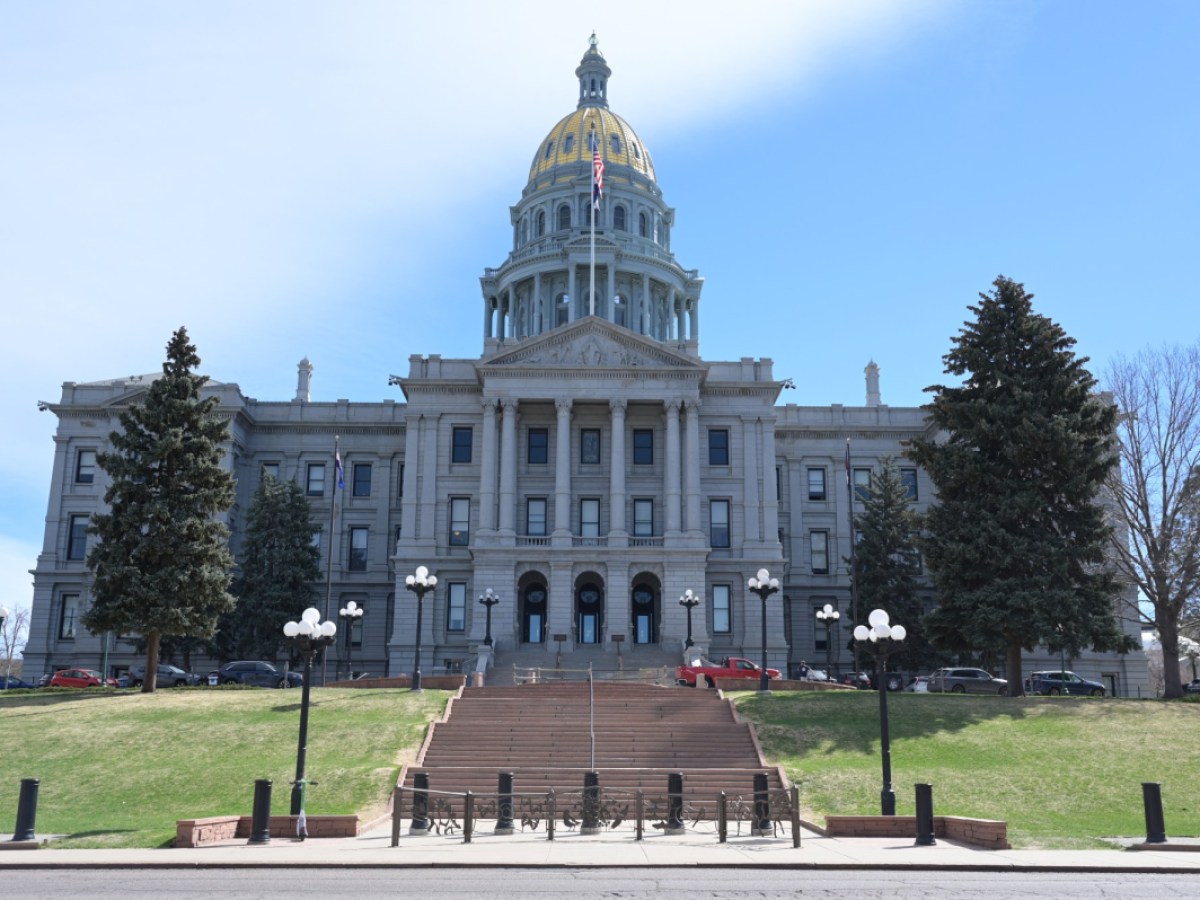 The Colorado State Capitol building in Denver photographed from ground level on a clear day, with the gold dome prominent, news photography style