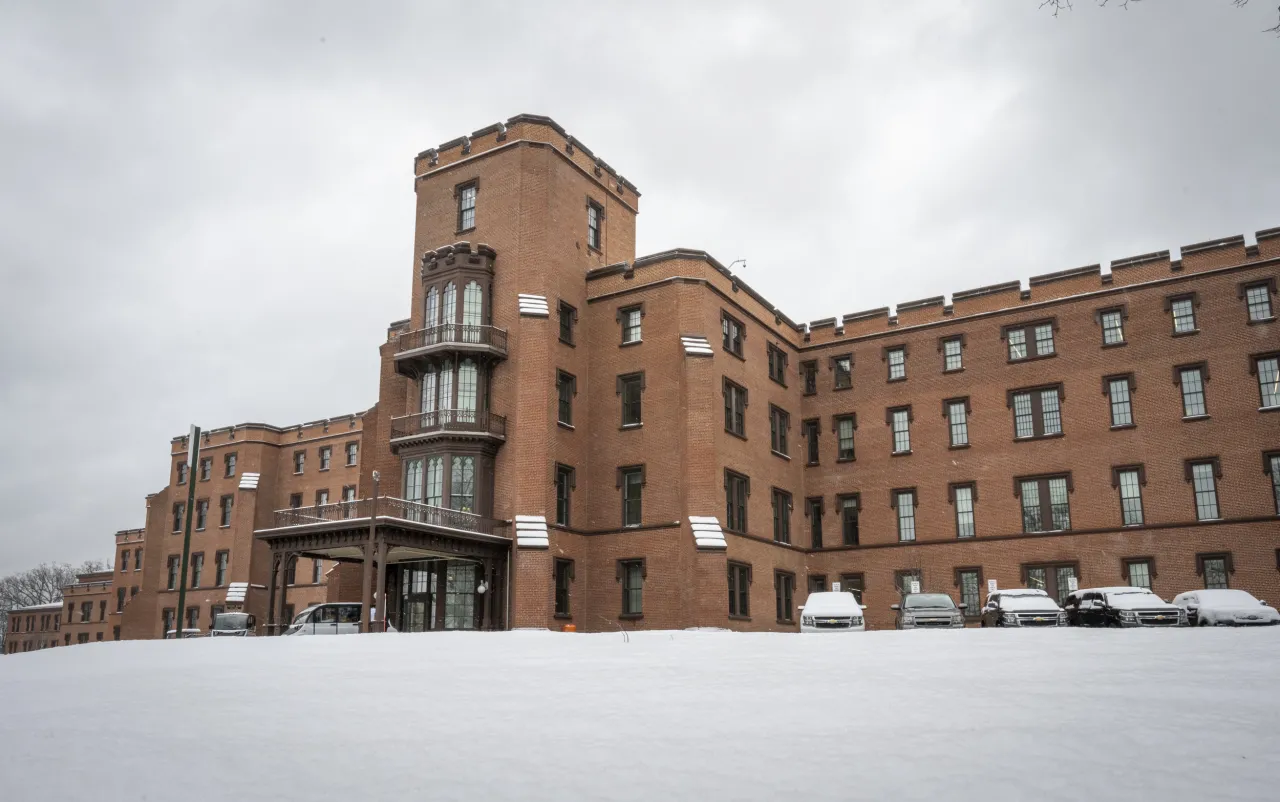 The Department of Homeland Security building exterior in Washington, D.C. with a DHS sign visible near the entrance, photographed in realistic daytime news photography
