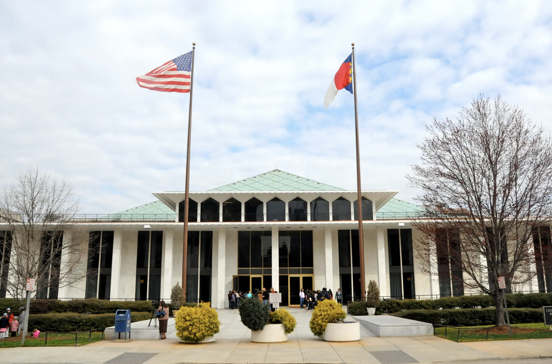 The North Carolina Legislative Building in Raleigh with pedestrians on the plaza, photographed from street level in a realistic news style