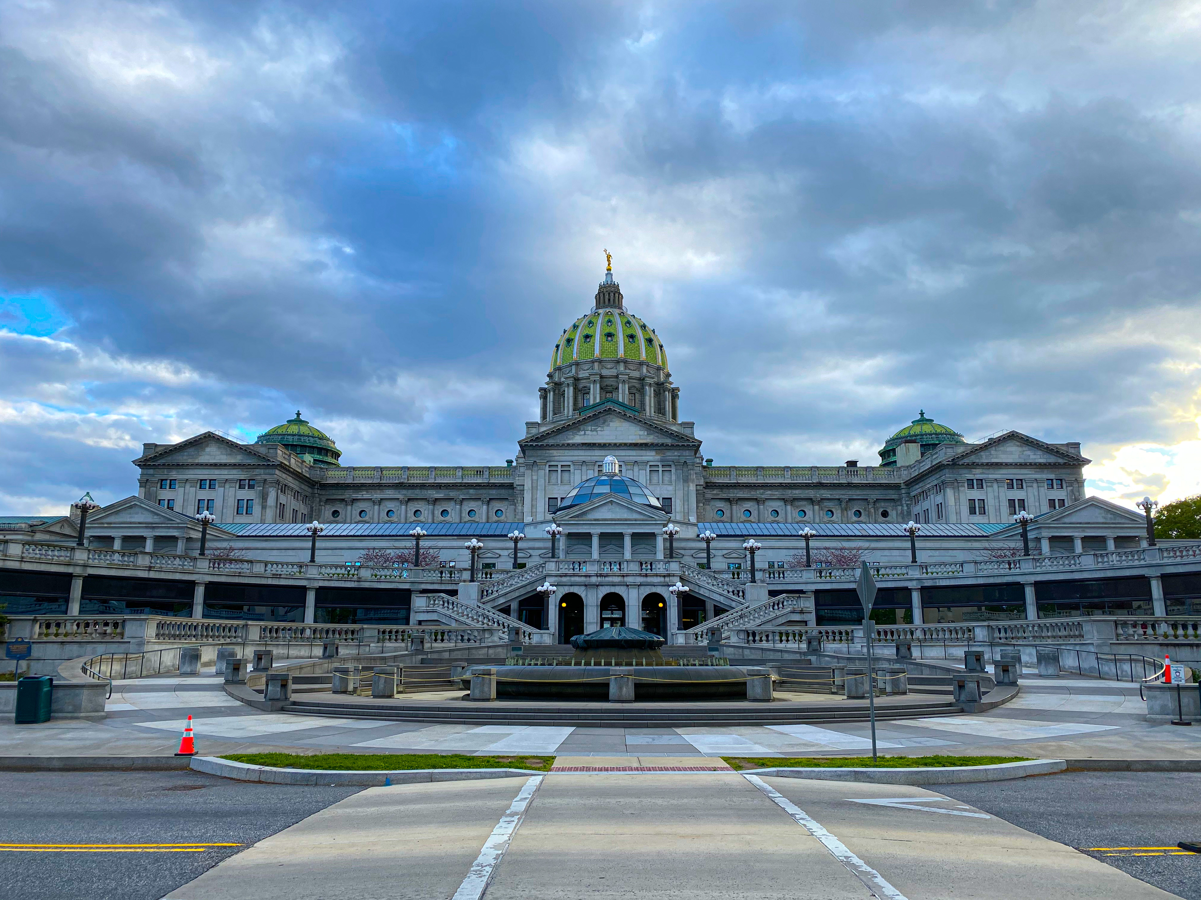 The Pennsylvania State Capitol building in Harrisburg photographed from street level with pedestrians nearby, news photography style