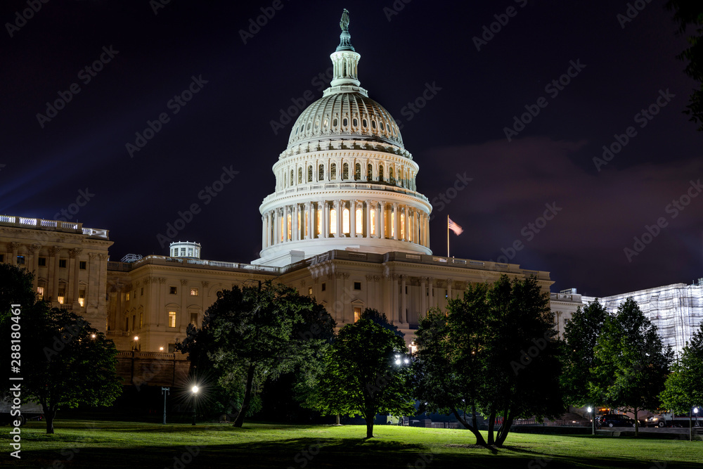 The United States Capitol building at night with lights glowing and a clear view of the dome, news photography style
