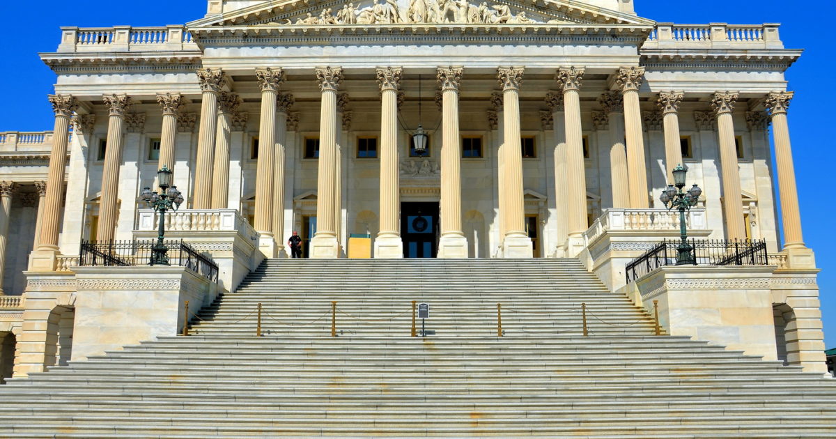 The United States Capitol building photographed from the grounds, with the Senate wing visible and visitors walking outside