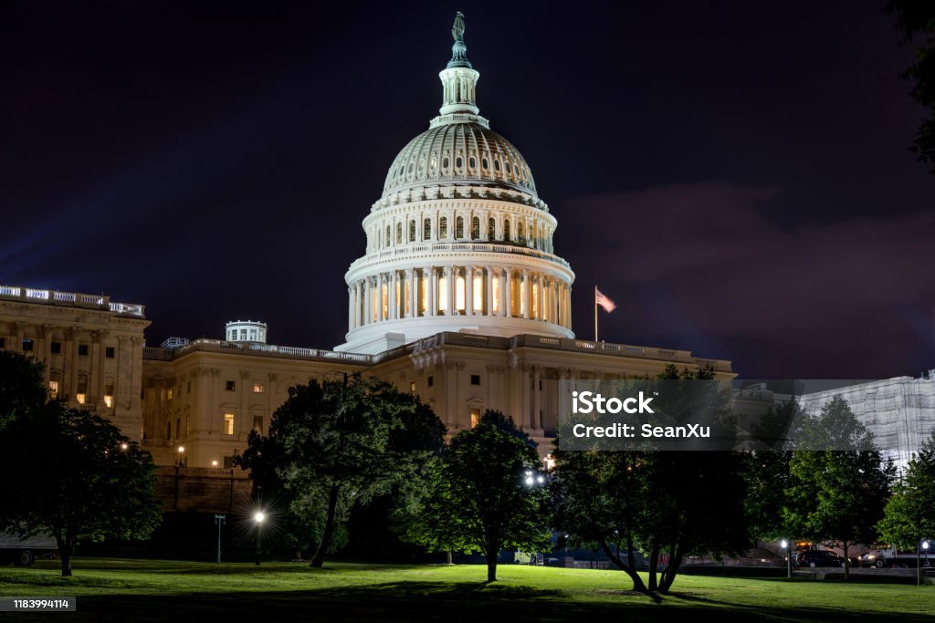 The United States Capitol in Washington, D.C. at dusk with warm lights glowing, photographed from the lawn with the dome centered