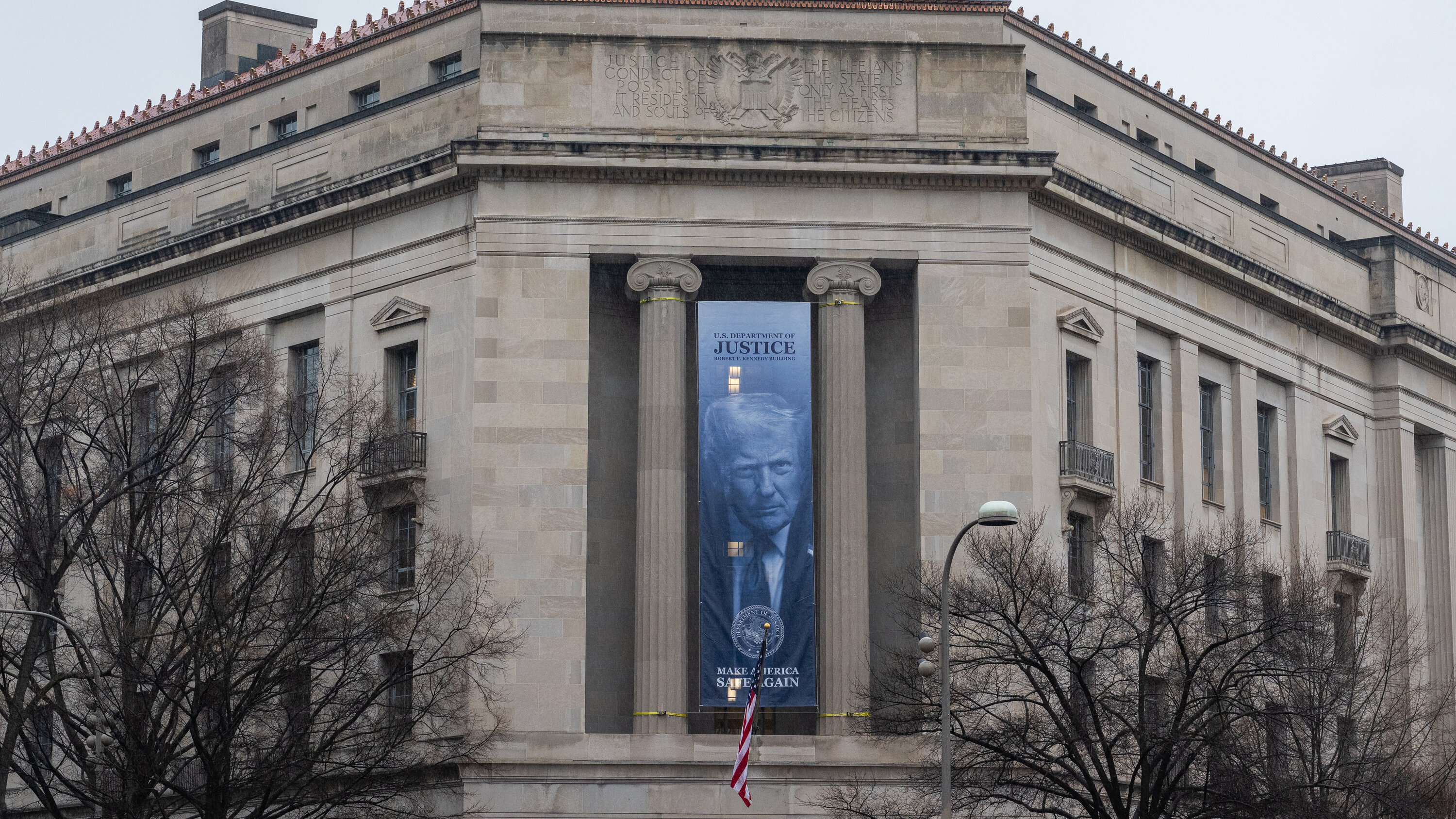 The United States Department of Justice headquarters building in Washington, D.C., photographed from street level with cars passing by, news photography style