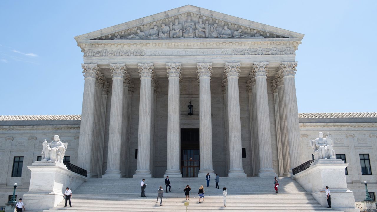 The United States Supreme Court building in Washington, DC, on a June morning in 2019 with people gathered on the front steps, news photography style