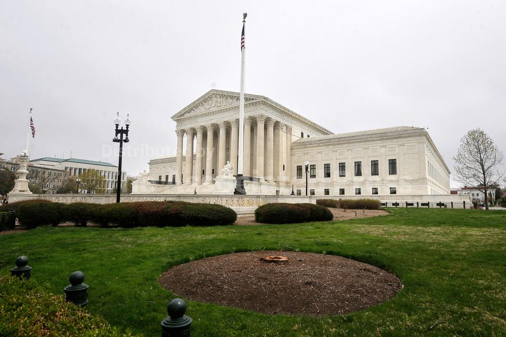 The United States Supreme Court building in Washington, D.C., photographed from the front steps in bright daylight with people walking in the background, news photography style
